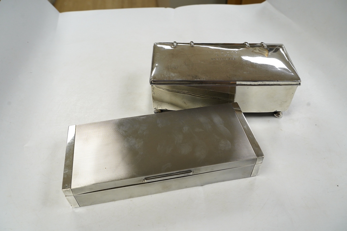 A George V engine turned silver cigarette box, by Padgett & Braham Ltd, London, 1935, 21.6cm and an earlier Irish silver cigarette box. Condition - poor to fair